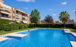 Piscina comunitaria al aire libre rodeada de edificios residenciales y zonas ajardinadas en un entorno urbano.