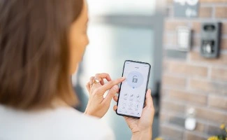 Mujer usando un smartphone para controlar el acceso de una cerradura inteligente en una vivienda.