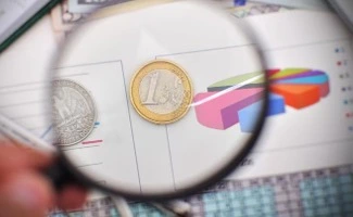 Lupa sobre informes económicos y gráficos, representando la revisión y transparencia de las cuentas en una comunidad de propietarios.
